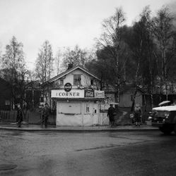 17. mai 1963. Dramatisk brann på Strømmens Værksted mens toget passerer Cornerbua på hjørnet av Strømsveien og Stasjonsveien. Fronten på brannbilen til høyre.