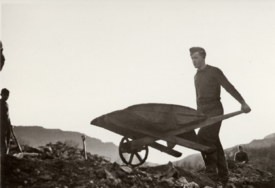 Mann med trillebår tilknyttet AT-leiren på Mo i Vikedal. Foto: Tore Juland/Karmsund folkemuseum
