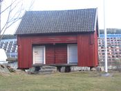 Stabbur ved Bånkall gård. Blokkene på Vestli ses i bakgrunnen. Foto: Stig Rune Pedersen