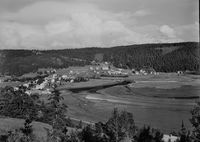 Vellamelen i Beitstad i 1955. Vi ser blant annet Beitstad samfunnshus og 1. byggetrinn på sentralskolen i Beitstad. Fotografen har stått på Fosnes, altså er bildet tatt fra nord. Foto: Ukjent / Nasjonalbiblioteket