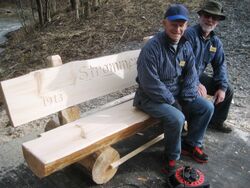 Alf prøvesitter benken til Strømmen Vels hundreårsjubileum 2013. Bygget av Egil Johnsbråten og Trygve Fledsberg (på bildet) og senere montert på St. Hansfjellet av de samme. Foto 2013 Steinar Bunæs.