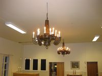 Her ser vi dei to lysekronene som kom på plass i kyrkja saman med ei rekke tilsvarande lampettar då det vart lagt inn elektrisitet i kyrkja i 1937. Dei vart montera i salen på Betel, bedehuset som vart soknehus, etter å ha vore teke vare på av Fyresdal bygdemuseum og i buret på prestegarden. Foto av Olav Momrak-Haugan 2013