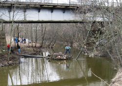 Samme bru fotografert under dugnad 2010. På den lille øya sto midterste pilar for enkeltsporsbrua fra 1865, og er her ryddet for trær som truet fundamentets stabilitet.