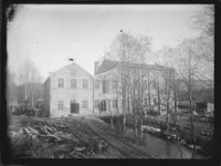 Nærbilde av forrige. Bygninger over elv. Men hvor? Foto: Marthinius Skøien (omkr. 1880-1910).