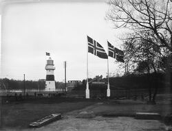 Området sett mot vest fra parkområdet med inngangsportalen mellom flaggstengene. Foto: Narve Skarpmoen/Nasjonalbiblioteket