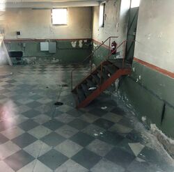 Fjernvarmeanleggets indre. Foto tatt gjennom vinduet viser at det var stor takhøyde, nå fullstendig tomt for utstyr. 2021 Steinar Bunæs.