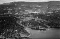 Skaugumsåsen sett fra Breivikbukta på Mellom-Nes. Til høyre øverst i bildet kan vi skimte Grosetkollen Sportskafè. Til venstre midt på bildet ser vi Holmen skole. Videre mot høyre Nedre Berger gård med Bergerjordene bakover mot Åstadryggen. Der gården og jordene lå finner vi i dag Nesbru videregående skole, Elektrisk Bureau og utbyggingsområde "Vestre Billingstad". Foto: Rolf Ingelsrud (1953).