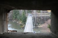 Utsikt mot den gjenoppbygde Gamle Fossum bru gjennom et av skyteskårene. Foto: Chris Nyborg (2013).