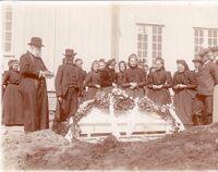 Gravferd på Moland kyrkjegard ved kyrkja sin nordre vegg. Presten er Ivar Mortensson og tidsrommet er 1910-1914. Fotograf er Olav S. Nylid.