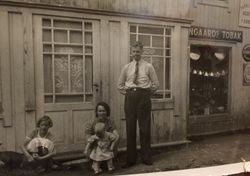 Familien Holmstad foran landhandleriet sitt i Østre Toten. Til høyre ser vi reklame for Langaards tobakk. Foto: Ukjent (fra privat album)