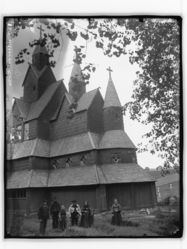 Kyrkja sett frå søraust, med bunadskledd følgje. Foto: Marthinius Skøien (omkr. 1890–1910).