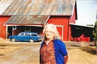 Helmine Paulsberg foran låven og Ford Taunus (ca 1962 modell) i Paulsberg. Foto: Ukjent, 1992