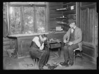 Fra skomakerverkstedet på Nordstrand. Mann såler sko. Foto: Narve Skarpmoen, Nasjonalbiblioteket, 1899-1930.