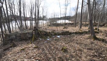Platået for den øverste og største isstabelen på Graffodden. Arealet er på ca. 760 m2. I bakgrunnen Nærsnes Grendehus og kirken. Isen kom fra Schwartzedammen (dammen ovenfor kirken) og ble send i isrenne det siste stykke ned mot stabelen. Ved uttak av is og lasting, ble isen sendt i renne ned til lasteplassen på odden nedenfor. (Foto: Victor Iversen 2021).