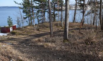 Kyststien passerer over platået der den midterste av isstablene på Graffodden lå. Går du ned mot det røde båthuset, kommer du til det nederste platået. Da ser du også grunnmuren til disse platåene, og har lasteplassen til venstre. Les om isstablene på Graffodden. (Foto: Victor Iversen 2021)