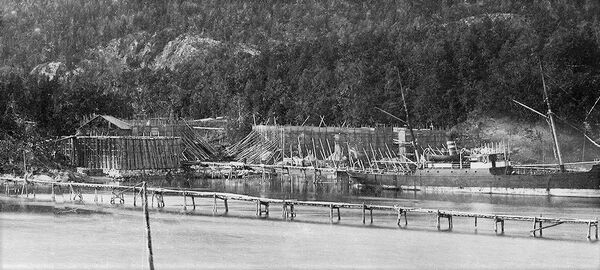 Dette bildet fra midten av 1890-tallet viser ett gjenstående ishus. De øvrige var da erstattet av de store isstablene. I forgrunnen ser vi den lange isrenna som gikk fra isstabelen på Mellomstranda langt ut i bukta. (foto fra AS Søndre Nærsnes)