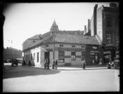 Opprinnelig bebyggelse i det daværende Jernbanetorget 6. Østbanebygningen skimtes gjennom gateløpet. Foto: Narve Skarpmoen (1899–1930).