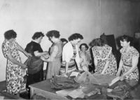 Damekoret i øvelseslokalet, men her i full gang med å prøve og sy drakter til Steinkjers byjubileum 7. mai 1957. Helga lager «stuss» på Sofie. Foto utlånt av Karin Kjølmoen