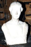 Byste av Titti Arenfeldt Omdal. Denne stod opprinnelig i gips på Gimle gård, men ble i 1996 erstattet med en støpt byste på samme sted.