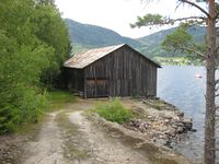 Lagerhuset til Åmdals kobberverk i Bandaksli. «Verkensbua». Lårdal i bakgrunnen. (Foto: Olav Momrak-Haugan, 2011)