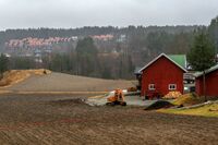 Gården Langbråten på Klemetsrud med rekkehusene i Øverliveien i bakgrunnen. Foto: Leif-Harald Ruud (2020)