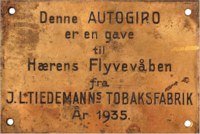 Messingskilt montert på venstre side av aktre cockpit på Hærens flyvåpens nr. 99 (Ill. via digitaltmuseum.no).