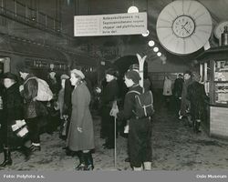 Forstadsbaneperrong på Nationaltheatret, med skilt om Holmenkollbanen og Sognsvannsbanen. Foto: Polyfoto (1950-åra).