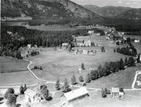Prestegarden fremst i biletet. Sentralt ser vi Gardar mot skogkanten og gamal og ny skulebygning på Gimle til høgre for denne. Foto: Widerøe 1955