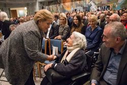 Statsminister Erna Solberg hilser på et av de aller eldste tidsvitnene, Ruth Goldstein, som deltok under seremonien i Oslo Rådhus. Ruth hadde flyktet med Carl Fredriksens Transport sammen med moren Elsa Schapow. Hun krysset grensen på sin 18-årsdag, 15. desember 1942. Faren og broren var blitt arrestert 24.oktober. Deres tragiske endelikt kom for en dag først etter krigens slutt.