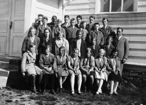 Konfirmantar 1930, bom fødde 1915/1916. Bildet er teke i prestegarden i Austrheim, der dei reiste for å førebu seg, saman med konfirmantane frå Austrheim. Presten (til høgre) var Ludvig Klåstad. Jenter 1. rekkje frå venstre: Solveig Herøy, Ruth Fredheim, Anna Rognsvåg, Margot Kongestøl, Olga Olsen, Marta Tangen, Helga Husa. 2. rekkje frå venstre: Anne Marie Husa, Petra Rognsvåg, Erna Fjeldheim, Synneva Rognsvåg, Jenny Gullaksen, Emma Ophaug. Gutar 3. rekkje frå venstre: Severin Stormark (litt gøymd), Martin Gullaksen, Anton Ophaug, Olav Stormark, Arthur Braathe, Ole Langedal. 4. rekkje frå venstre: Ditlef Mongstad, Einar Eilertsen (Smines), Olai Mongstad, Arne Storemark, Ingvar Berg, Andreas Gudmundsen Husa.