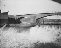 Damsfossen med brua og med Hjellevannet bak. Foto: Marthinius Skøien/Nasjonalbiblioteket (1880–1910).