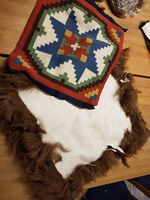 Bildet viser prosessen med å sy en pute av skinnfell og åkle. Puta har skinn på baksiden. Åkleet festes til brudekanten, en kant som sys på rundt åkleet for å lage en innramming. Brudekanten sys gjerne sammen av biter. Åkleet er i dette tilfellet en pute vevd av Astrid Geithus i Balestrand.