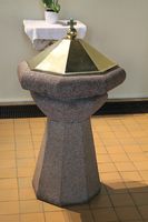 Døpefont i granitt med messingdeksel.