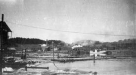 Fartøyet i Hølen ved Vestfossen. I bakgrunnen ser vi et damplokomotiv på vei mot Kongsberg og helt til venstre Eker Dampsag. Foto: Anders Lauritzen/Eiker Arkiv