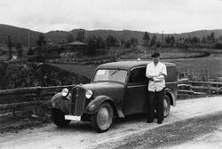 Per Bottegård foran en DKW som tilhørte Brødrene Løver - Den ble brukt til å frakte mat til forlegningene i fredsdagene - I bakgrunnen: Huset til Tajet på Skretteberg, som tyskerne brukte til lyttepost.