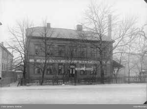 Den tidligere bygningen på tomta, hvor Caroline og Hans Andersen hadde kafe 1883-1893. Brødrene Hals` konsertlokale i venste bildekant. Foto: Gustav Jensen/Oslo Museum (1899).