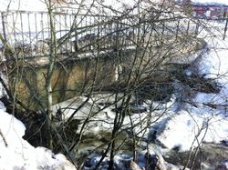 Bru i Skjærvaveien 2012. Dagens bru i betong er nesten skjult av krattskog.