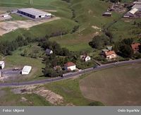 Flyfoto av Strømsveien fra 1962. I dette området på Alnabru, hvor det på bildet er villabebyggelse, ligger det nå industri, handelsbedrifter og godsterminaler. Foto: Ukjent/Widerøes Flyveselskap/Oslo byarkiv (1962).