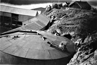 Utsikt over oljetanken på Kvedfjord sildoljefabrikk mot Kvæfjorden og fjellene i bakgrunnen. Foto: Ukjent. Utlånt av Anny Sørensen.