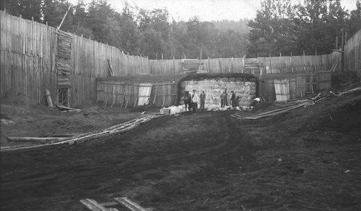 ISSTABEL PÅ FLATSTRANDA 1915-1925. Bildet viser at kun en liten del av den tidligere store gamle isstablen er i bruk. Høyden på isstablen er også redusert. Da første verdenskrig brøt ut falt markedet kraftig. Økonomisk krise og utvikling av kjøleteknologien gjorde at det store markedet aldri kom tilbake. Det ble ikke lenger bruk for de store isstablene. Konstruksjonene sto fremdeles der, men man brukte kun en liten del. (Foto fra Knut Baarsrud)