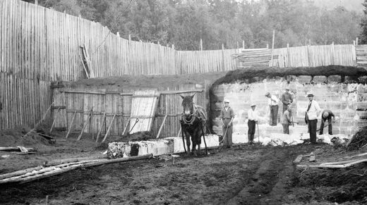 UTTAK AV IS PÅ FLATSTRANDA 1915-1925. Bildet viser hvordan isstablene ble avdekket og isen dratt på "ledere" ut av stabelen. Framme ved brygga ble isblokkene vasket, før de ble lastet ombord i skipene. Mannen med hvit stråhatt er Adam Baarsrud. (Foto fra Knut Baarsrud)