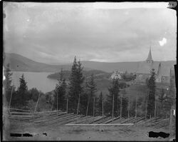 Kirkestedet sett fra sør, prestegården til venstre. Foto: Marthinius Skøien/Nasjonalbiblioteket (1880-1910).