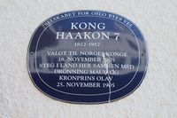 Blå plakett til minne om kong Haakon VIIs, dronning Maud og kronprins Olavs ankomst til Norge i 1905. Foto: Chris Nyborg (2013)